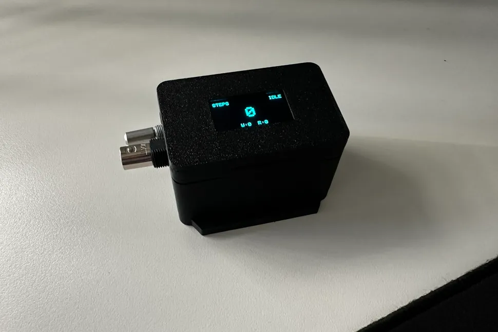 The finished tracker in a black printed enclosure, OLED lit and showing a step count
